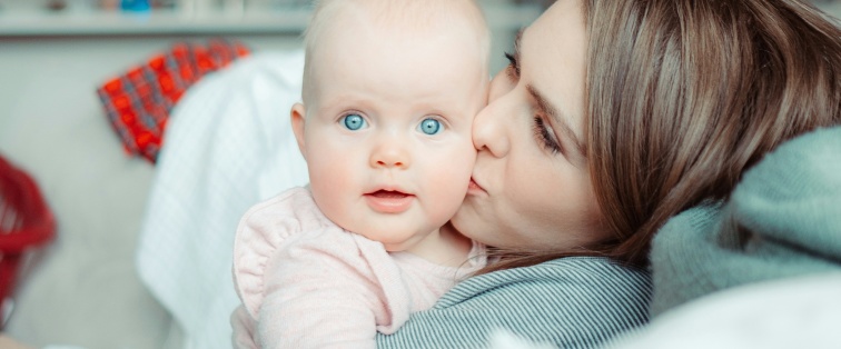mother kissing baby with blue eyes